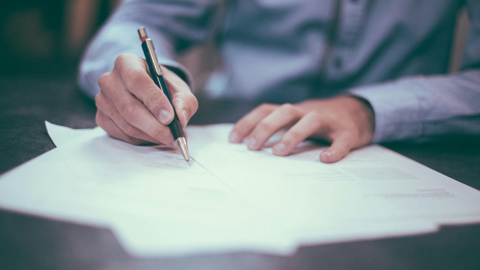 A clinician writing notes on paperwork at a desk