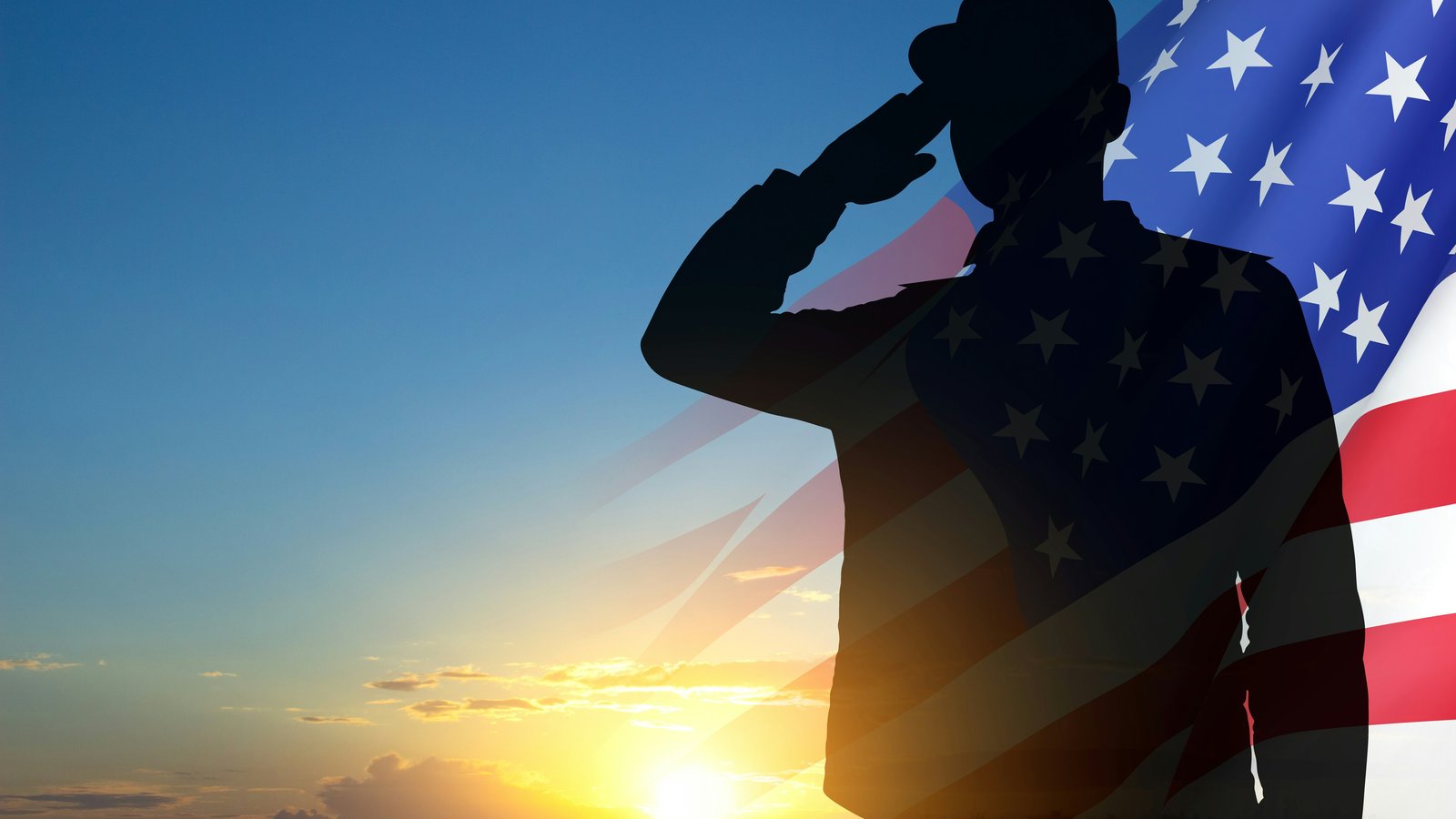 Silhouette of a soldier saluting at sunset with an American flag in the background